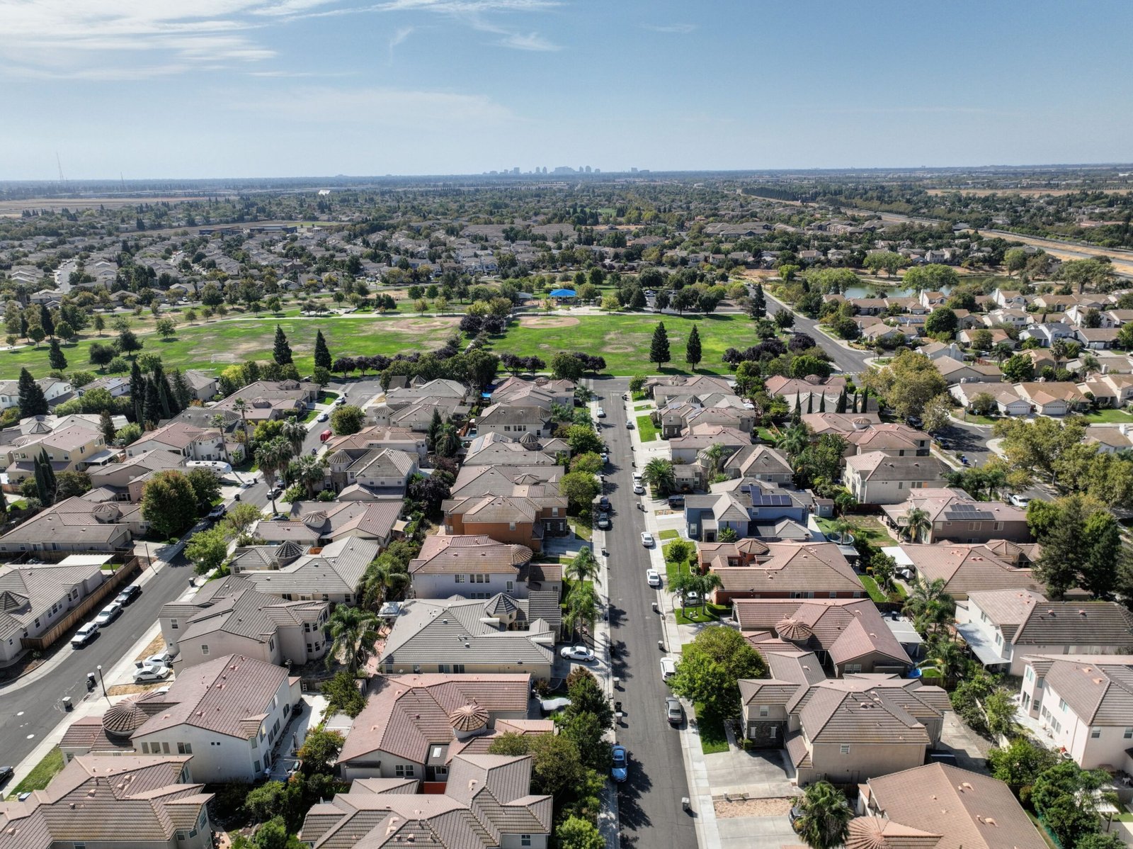 What Riverside Homeowners Should Know About Today’s Real Estate Market Scenic aerial view of Sacramento suburb with rows of houses and lush greenery on a sunny day.